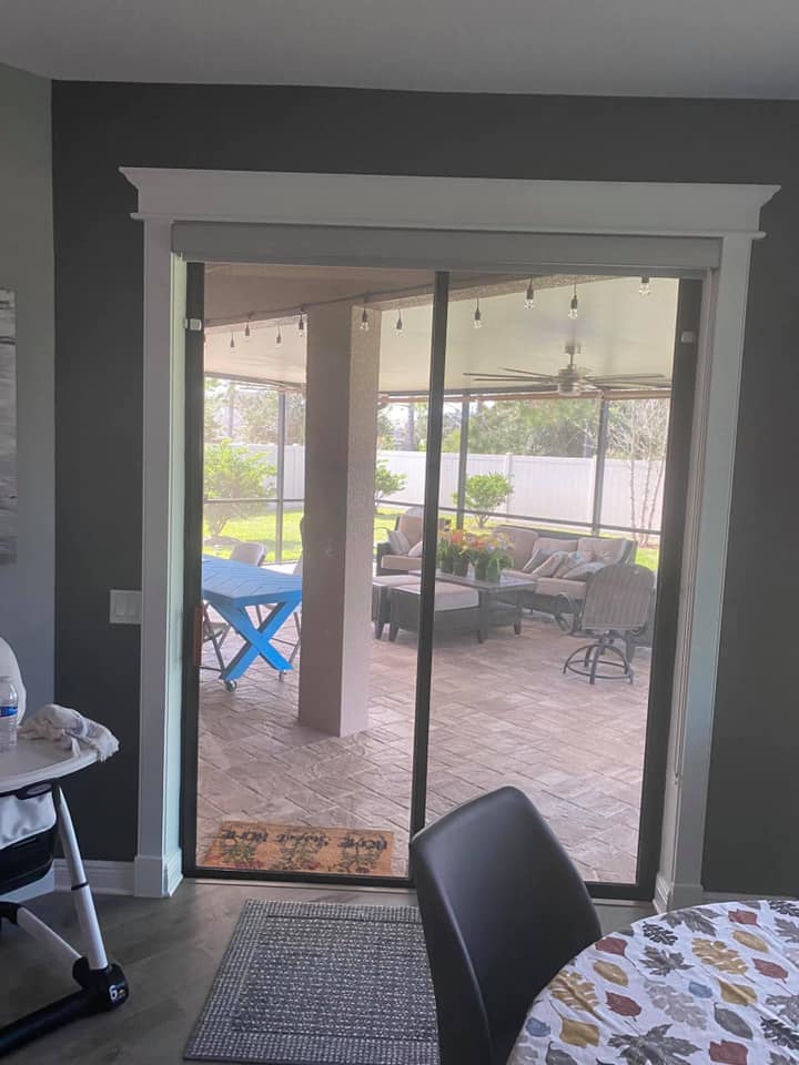 Sliding glass doors open to a covered patio with outdoor furniture and a blue folded chair.