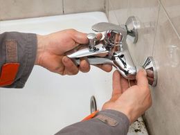 Plumber hands fixing water tap in a bathroom Plumber hands fixing water tap in a bathroom