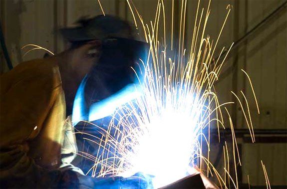 A man is welding a piece of metal with sparks coming out of it.