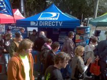 A crowd of people are gathered in front of a directv tent