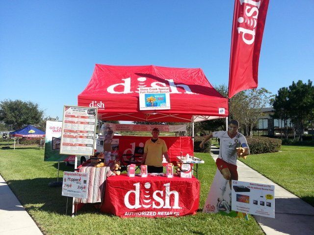 A man stands behind a table that says dish on it