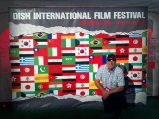A man stands in front of a sign that says dish international film festival