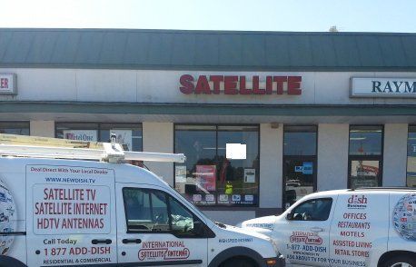 Two satellite vans are parked in front of a store