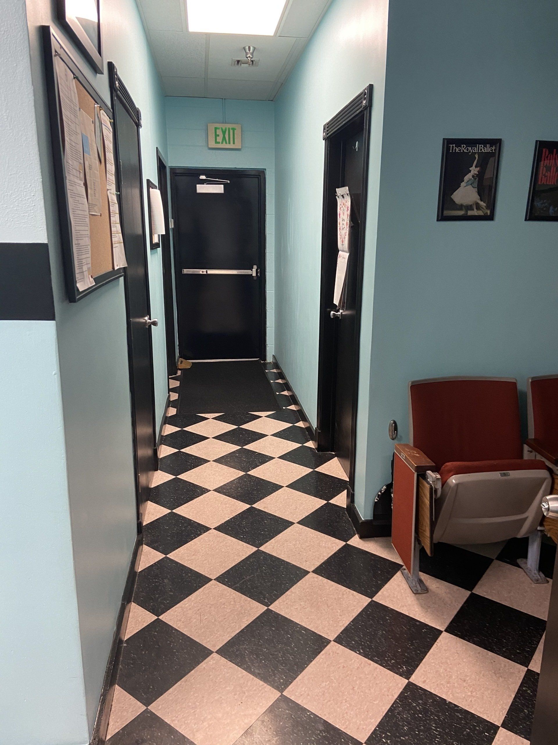 A hallway with a checkered floor and an exit sign
