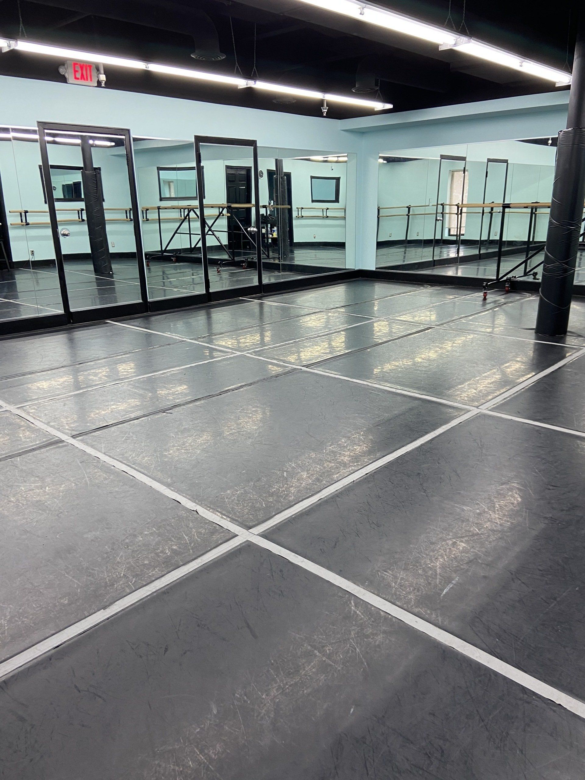 A dance studio with a lot of mirrors and a red exit sign