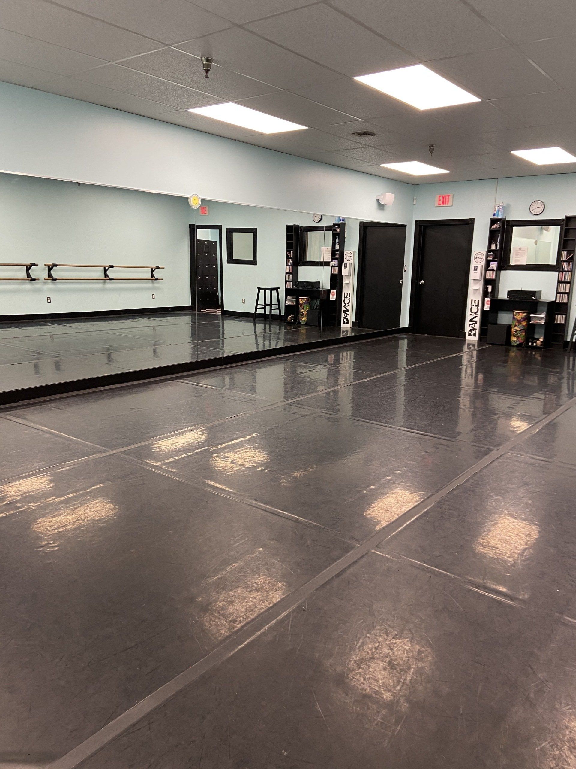 An empty dance studio with a large mirror on the wall.