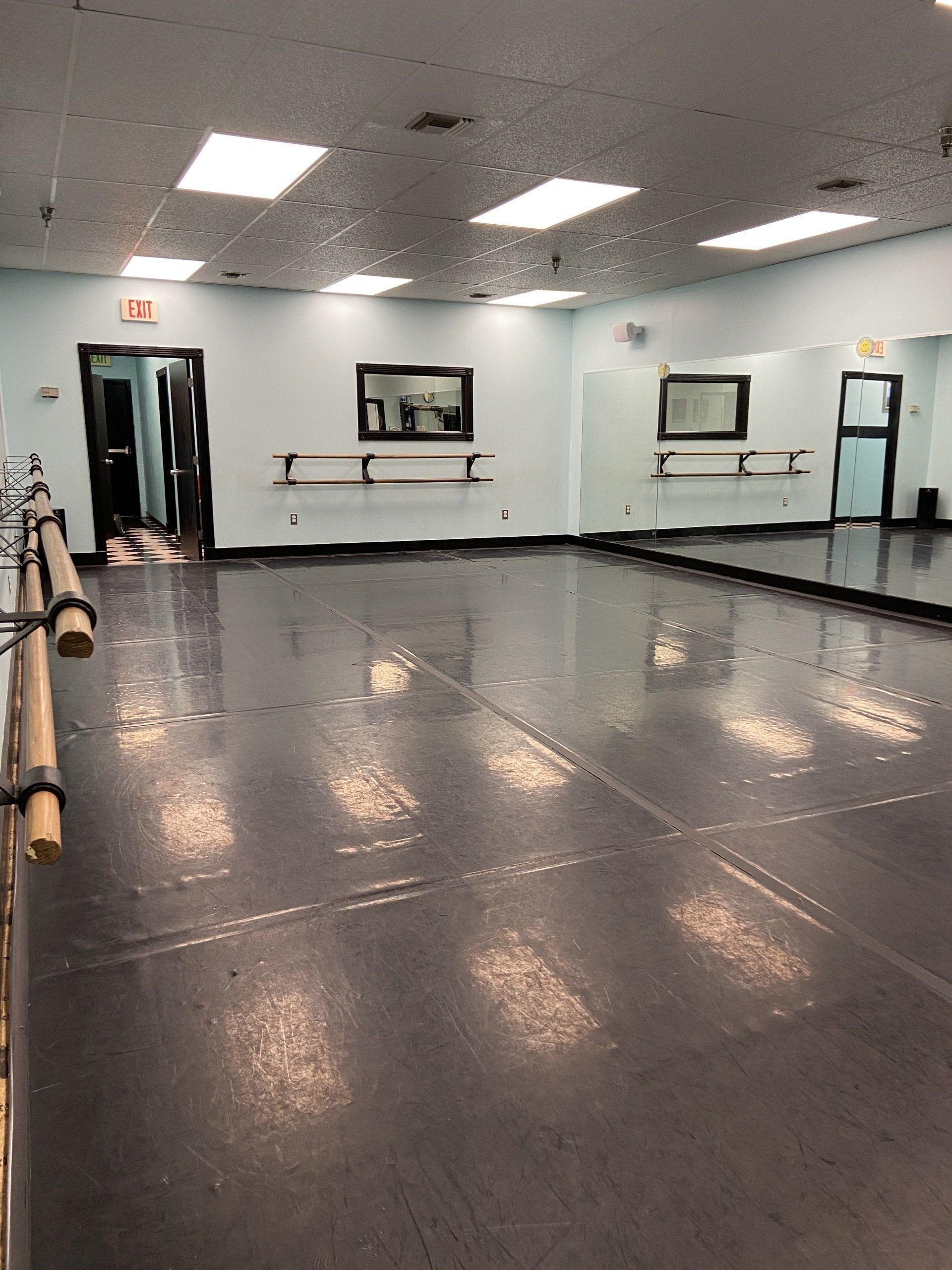 A large empty dance studio with a large mirror on the wall.