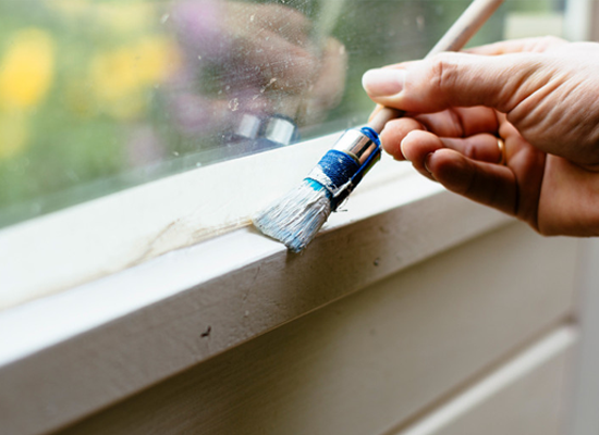 Man painting inside of a kitchen door white.