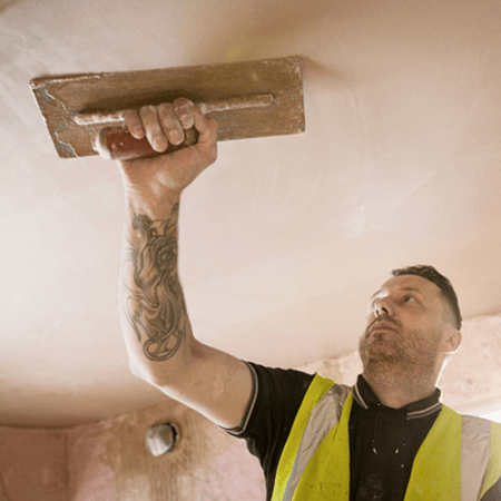 Construction worker with tattoo plastering ceiling