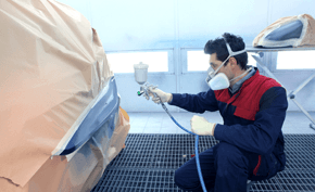 Mechanic respraying a car with grey spray paint