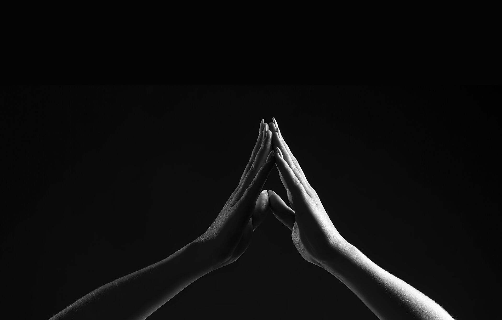 Two hands touching fingertips, forming a triangular shape against a dark background.