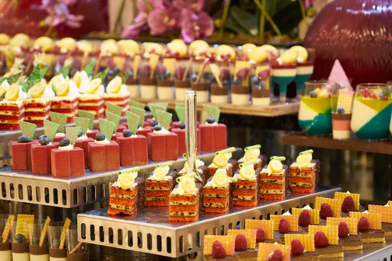 Dessert buffet with layered cakes, mousses, and parfaits on tiered serving trays.