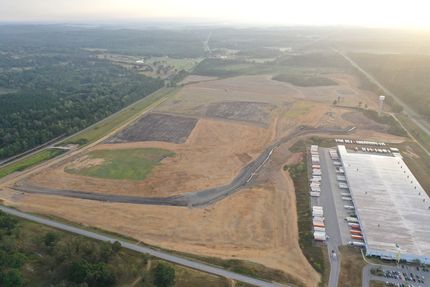 Aerial view of a large industrial area with a landfill, warehouse, and parking lot.