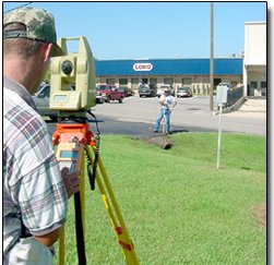 Land Surveying — Meridian, MS — Engineering Plus, Inc. Surveyor using equipment to measure land near a building with