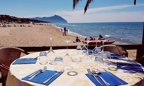 un tavolo apparecchiato e vista di una spiaggia e del mare