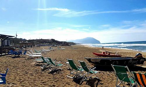 una spiaggia con sdraio, pedalò e vista del mare