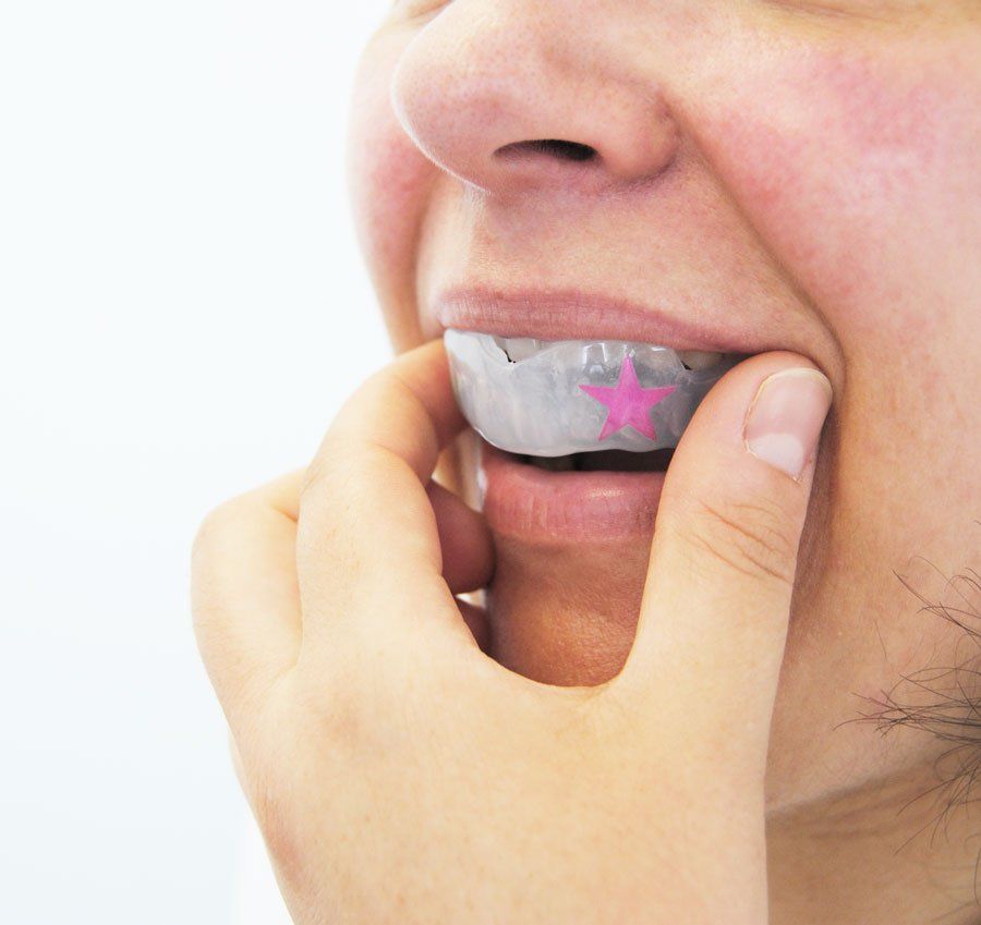 mulher a colocar protector bucal desportivo