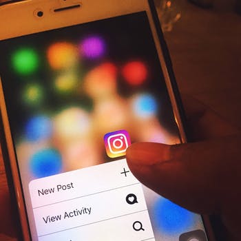 A person is pointing at the instagram app on their phone