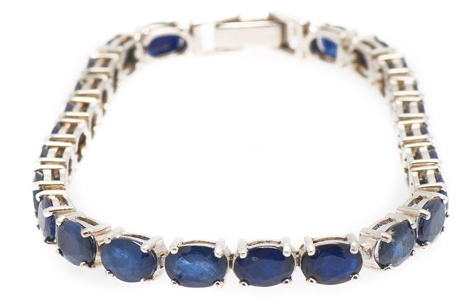 A silver bracelet with blue sapphires on a white background