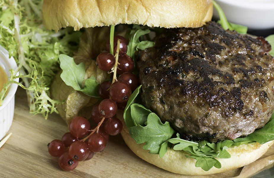 A hamburger with lettuce and red currants on a bun