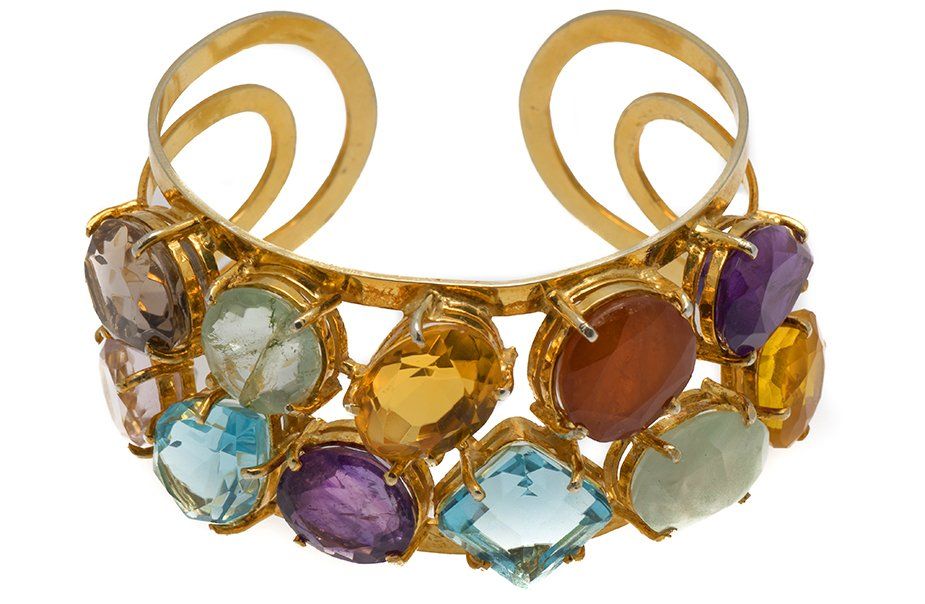 A gold bracelet with various colored stones on it