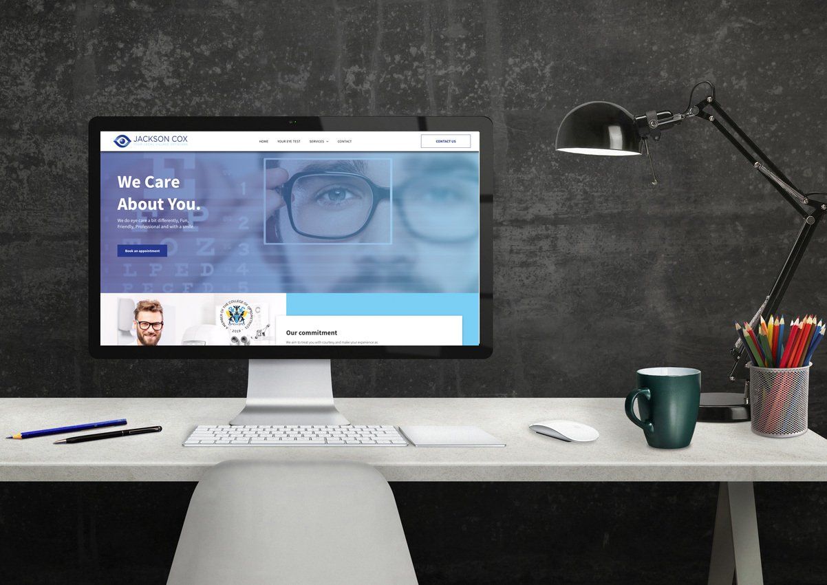 A computer monitor is sitting on a desk next to a lamp.