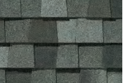 Close-up of asphalt shingles, varying shades of gray, overlapping pattern.