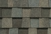 Close-up of asphalt roof shingles in shades of gray, brown, and blue.