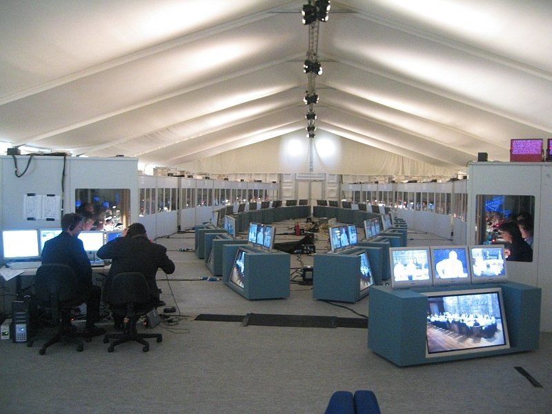 Een grote ruimte met veel monitoren en mensen die aan bureaus zitten