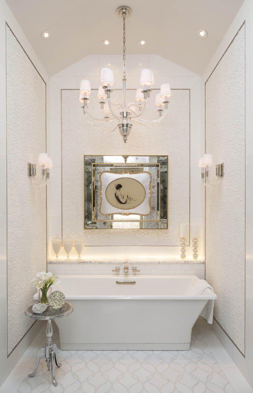 A bathroom with a tub a mirror and a chandelier