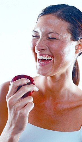 Dental Implants Cost — Woman Holding Apple in Roseville, MI Dental Implants Cost — Woman Holding Apple in Roseville, MI