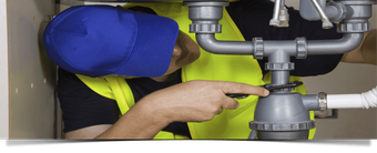 plumber fixing leaky pipes under a sink