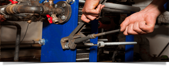 plumber tightening a bolt on a commercial plumbing system
