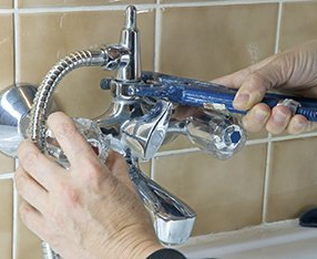 plumber fixing a faulty bath faucet