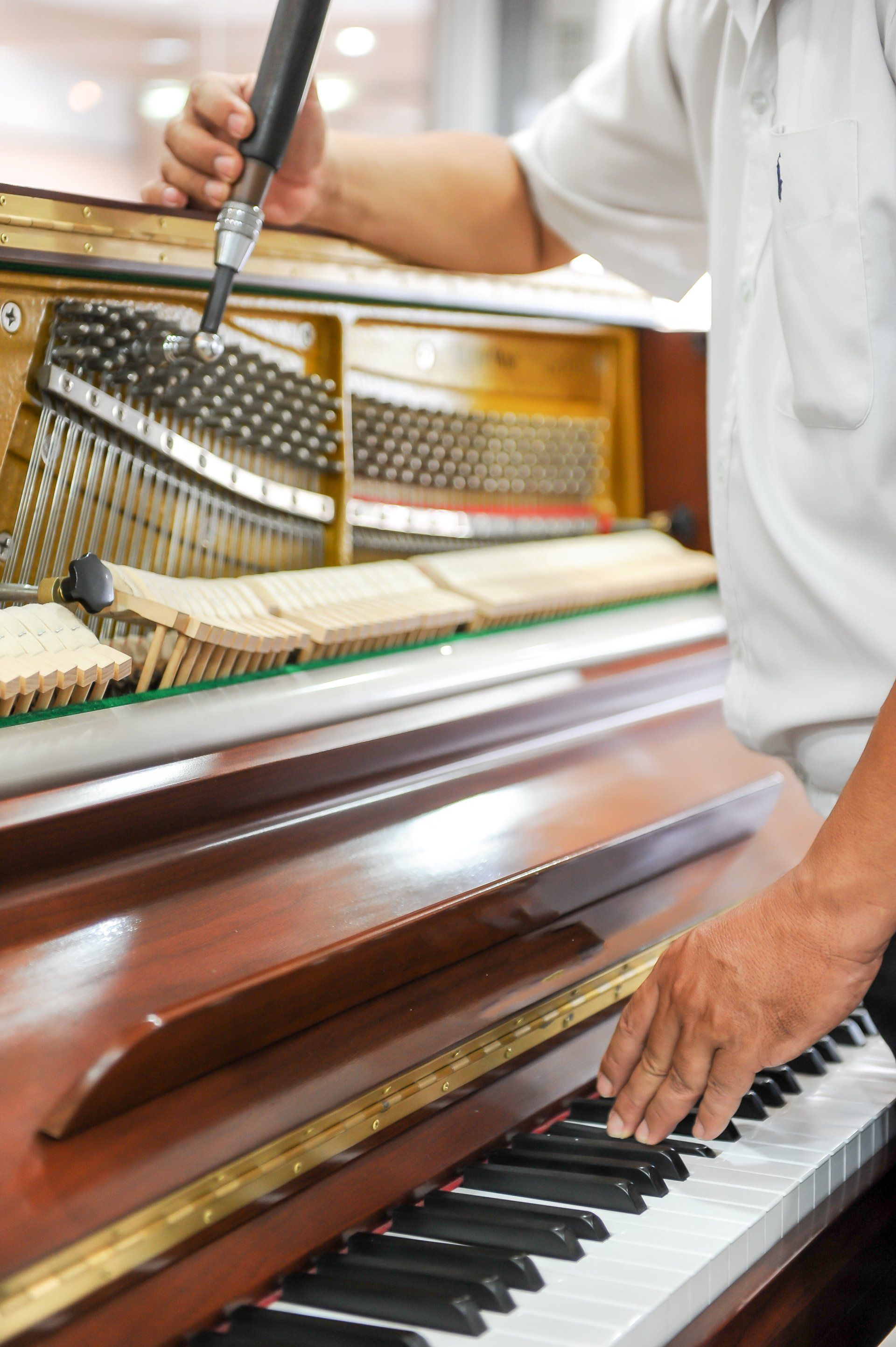 a man is fixing a piano with a screwdriver .