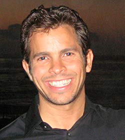 Smiling man in a black shirt against a dark background