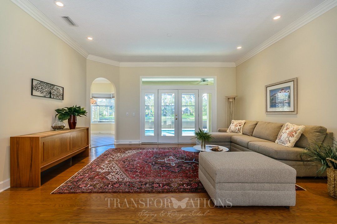 A living room with a couch , ottoman and rug.