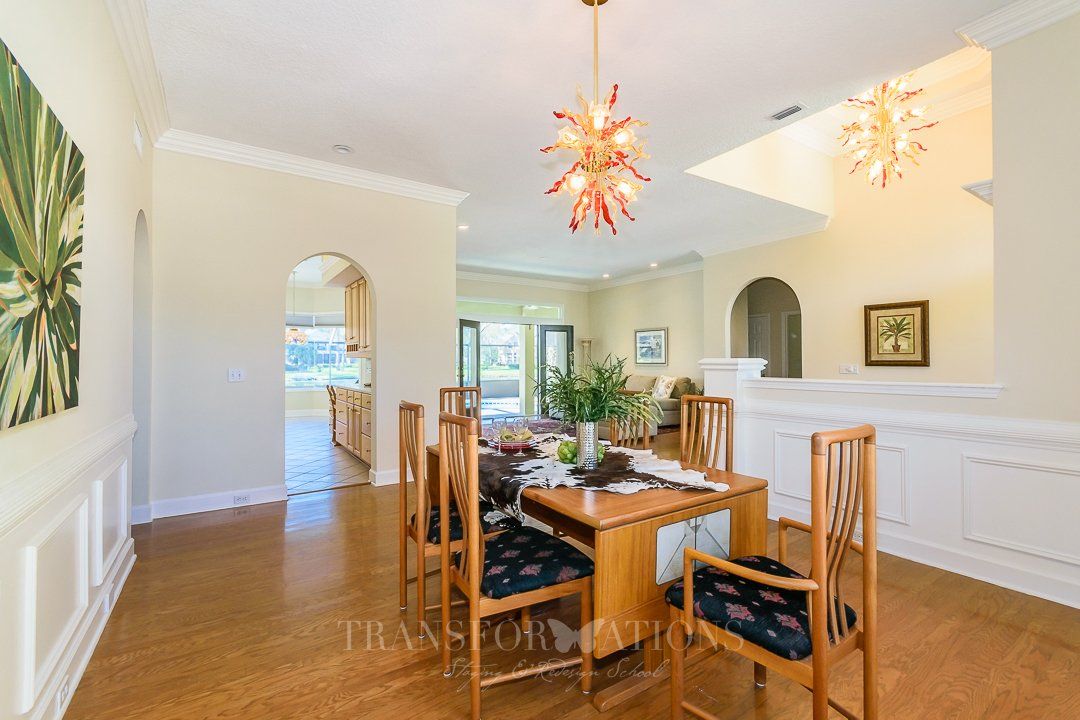 A dining room with a table and chairs and a chandelier hanging from the ceiling.