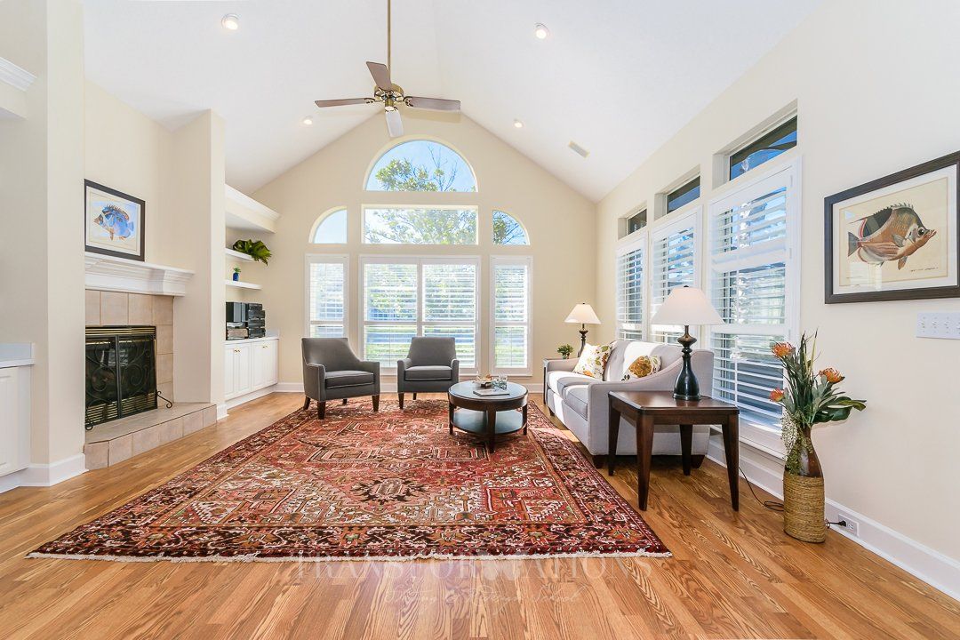 A living room with a fireplace , couch , chairs , table and rug.