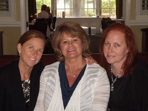 Three women are posing for a picture together in a restaurant.