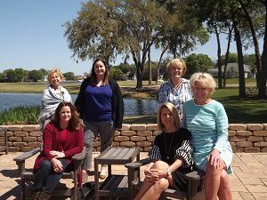 A group of women are posing for a picture in front of a lake.