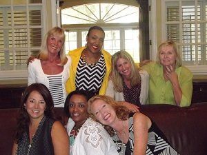 A group of women are posing for a picture while sitting on a couch.