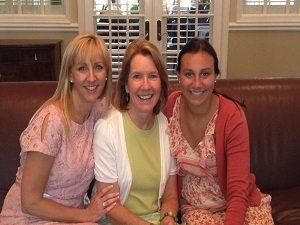 Three women are posing for a picture while sitting on a couch