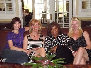 Four women are posing for a picture while sitting on a couch