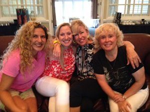 Four women are posing for a picture while sitting on a couch