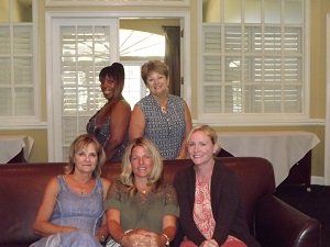 Four women are posing for a picture while sitting on a couch