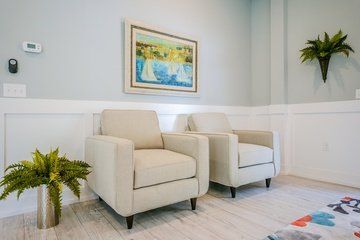 A living room with two chairs and a painting on the wall.