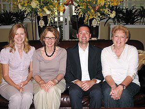 A group of people are sitting on a couch posing for a picture.