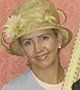A woman wearing a hat and a lei is smiling.