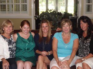 A group of women are posing for a picture while sitting on a couch.